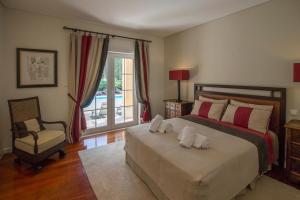 a bedroom with a large bed and a chair at Villa Buganvilia III in Aroeira +35 photos