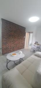 a living room with a table and a brick wall at Apartman Katić 2 in Odžak