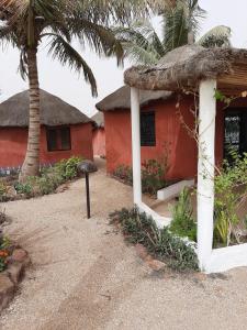 a red house with a thatched roof and a palm tree at lasofia in Mbodiène