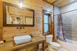 a bathroom with a sink and a toilet and a mirror at Low Rider Lodge - Backs to Pine Forest and ATV Trail Access from Driveway in Broken Bow +176 photos