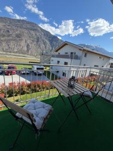 a deck with a chair and a table on a balcony at Appartement Vue Montagne Vignoble Cosy Valais in Chamoson