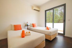two beds with orange pillows in a room with a window at Villa Phi Phi - com piscina privada em Vilamoura in Quarteira +42 photos