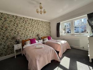 two beds in a room with pink blankets at The Nags Head - Room only accommodation in Lyme Regis
