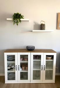 a white cabinet with glass doors and a plant at Apartamento A pie de Playa in Miño