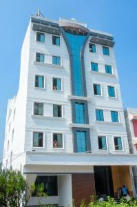a tall white building with people in the windows at MGR Residency in Pondicherry