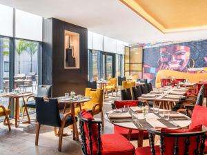 ein Restaurant mit Tischen und Stühlen und einem Gemälde an der Wand in der Unterkunft Movenpick Hotel Abidjan in Abidjan