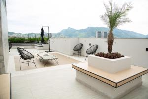 a patio with chairs and a palm tree on a roof at Loft Moderno Vista Mar - 14 Minutos De Copacabana in Rio de Janeiro