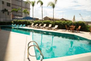 a large swimming pool with chairs and palm trees at Loft Moderno Vista Mar - 14 Minutos De Copacabana in Rio de Janeiro