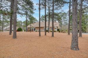 a house with a group of trees in front of it at Pinehurst Condo ~ 2 Miles to Downtown & Resort! in Pinehurst