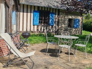 a patio with a table and chairs and a grill at La maison bleue in Reux