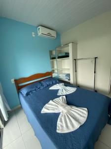 a bedroom with a blue bed with two flowers on it at Pousada Baia dos Golfinhos in Governador Celso Ramos