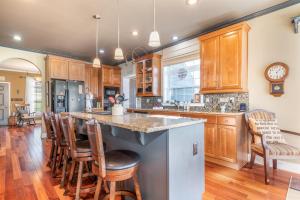 a kitchen with wooden cabinets and a island with bar stools at Pool Table, Massive Balcony, Firepit, & Spacious! in Sherrills Ford
