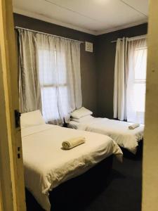 two beds in a room with two windows at Corfield in Durban