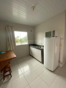 a kitchen with a white refrigerator and a window at Pousada Baia dos Golfinhos in Governador Celso Ramos