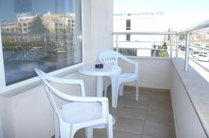 a balcony with two chairs and a table and a window at Family Hotel PUDEV in Sunny Beach