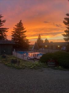 a sunset over a swimming pool with a fence at North Winds Lodge LLC in Bowman