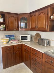 a kitchen with wooden cabinets and a microwave at Spacious House in Sagres with Private Patio & BBQ in Sagres +17 photos
