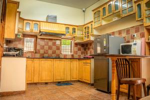 a kitchen with wooden cabinets and a refrigerator at White House By Kulut in Shamshi