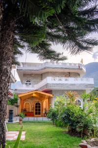 a large building with a tree in front of it at White House By Kulut in Shamshi