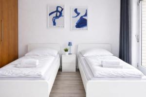 two beds in a room with white walls at Exklusive Studio-Apartments mit Balkon in Bad Rothenfelde