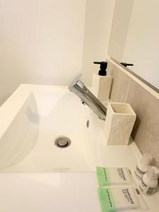 a white bathroom with a sink and a mirror at Studio Prestige, Cocon de Charme & Confort in Saint-Quentin