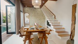 a dining room with a table and chairs and a staircase at Enso Villa and Hotel in Munggu