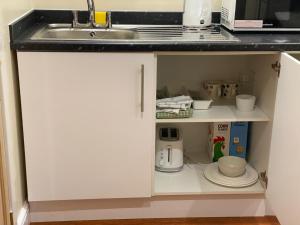 a kitchen counter with white cabinets and a sink at Standish Haven Ensuite Room in Standish