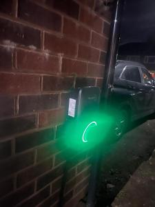a green electric car parked next to a brick wall at Standish Haven Ensuite Room in Standish