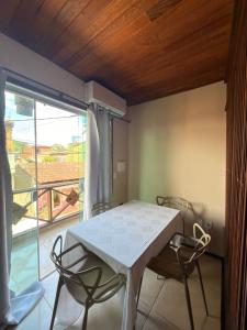 a white table and chairs in a room with a balcony at Pituba Vile - Apartamento Mandala in Itacaré
