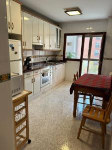 a kitchen with white cabinets and a table in it at Avilés para Visitar in Avilés