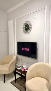 a living room with two chairs and a tv at Luxury Private Room Canal Rd Near Galleria in Faisalabad