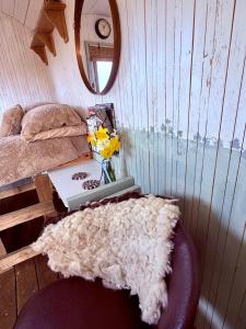 a room with a bed and a table with a vase of flowers at The Black Sheep Shepherd's Hut in Prestrie