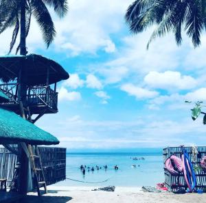 a beach with people in the water and palm trees at Seawave Beach and Dive Resort in Lobo