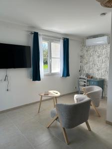 a living room with two chairs and a table and a tv at Ô Ptit Verger in Coulon