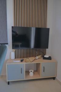 a flat screen tv on top of a wooden tv stand at Aithra Suite - Europa Hotel in Korinos