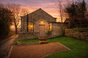an old stone house with a door in a yard at The Old Chapel, Peak District in Bamford