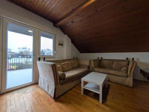 a living room with two couches and a large window at Spacious Condo w Terrace & Piano in Sesvete