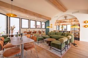 a restaurant with green furniture and tables and windows at Hôtel Villa Maïtia in Ustaritz