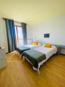 two beds in a room with wooden floors and windows at Hôtel MAS DE LAYALLE in Saintes-Maries-de-la-Mer