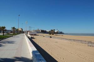 a sandy beach with palm trees and the ocean at Isabella Chipiona in Chipiona