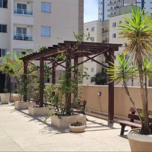 a pergola and a bench in a courtyard with palm trees at Apartamento Exec Premium Queen Bed Centro-Taubate in Taubaté