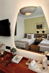 a hotel room with two beds and a desk with a mirror at Hotel Turist - City Center in Skopje