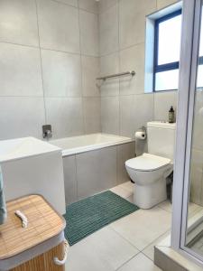 a bathroom with a toilet and a tub and a sink at Beach Haus Unit 1 in Cape Town +12 photos