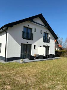 a white house with black windows and a yard at VILLA SOLARIS Ustka - PENSJONAT Z 2026R,ROWERY GRATIS, WYPOCZYNEK tylko DLA DOROSŁYCH ! in Ustka