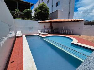 a swimming pool next to a building with a house at Airport subway apartment in Lauro de Freitas