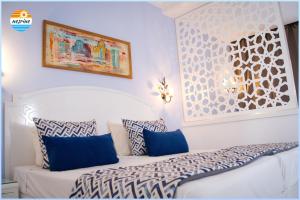 ein Schlafzimmer mit einem Bett mit blau-weißen Kissen in der Unterkunft Hotel Nesrine Hammamet in Hammamet + 20 Fotos