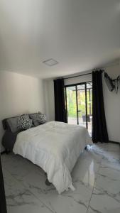 a white bedroom with a bed and a large window at Casa Benedicion in Pavones