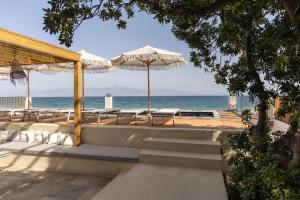 a beach with chairs and umbrellas and the ocean at Cavo Dio 8 - Beachfront bliss - Cozy Apt Pool Sunset in Káto Dhiminión