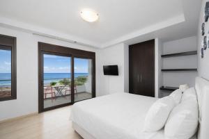 a white bedroom with a bed and a view of the ocean at Villa Metis in Lachania +28 photos