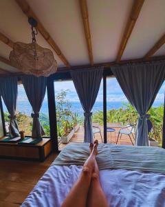 a person laying on a bed in a room with windows at Casa Alta Colombia, ecolodge con vistas, Pereira in Dosquebradas